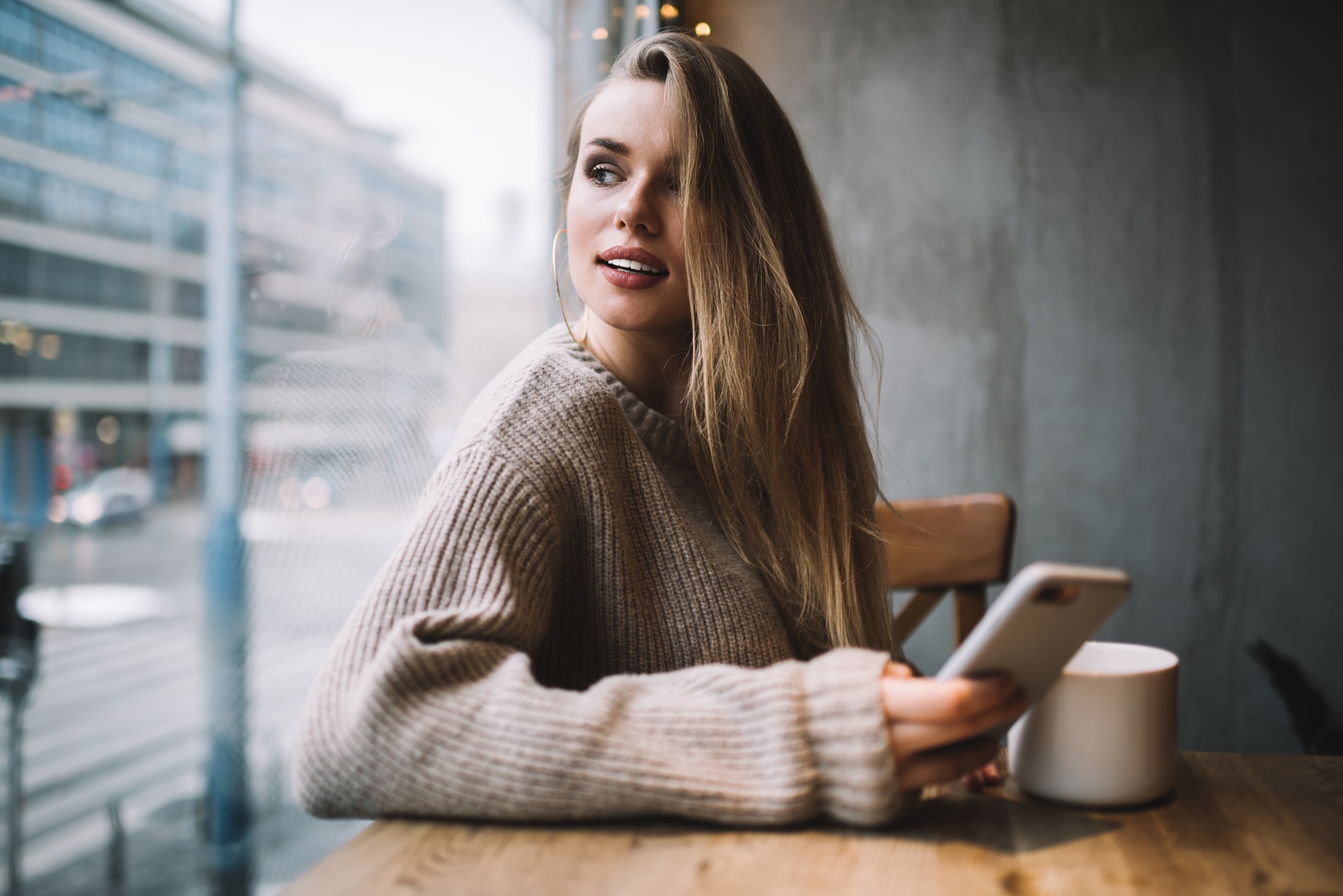 pensive hipster girl with mobile gadget pondering on online phoning